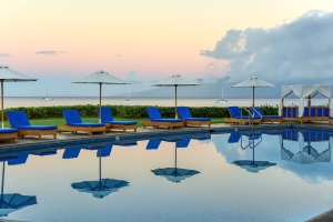 There are lounge chairs and parasols by the pool